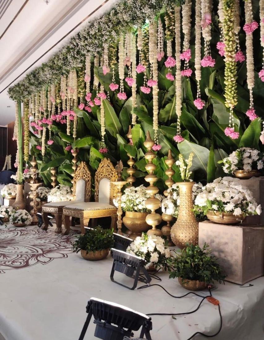Banana leaf backdrop with gold pillars and throne chairs