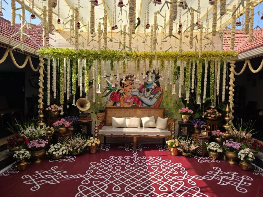 Courtyard ceremony setup with painted backdrop, brass pots and kolam floor
