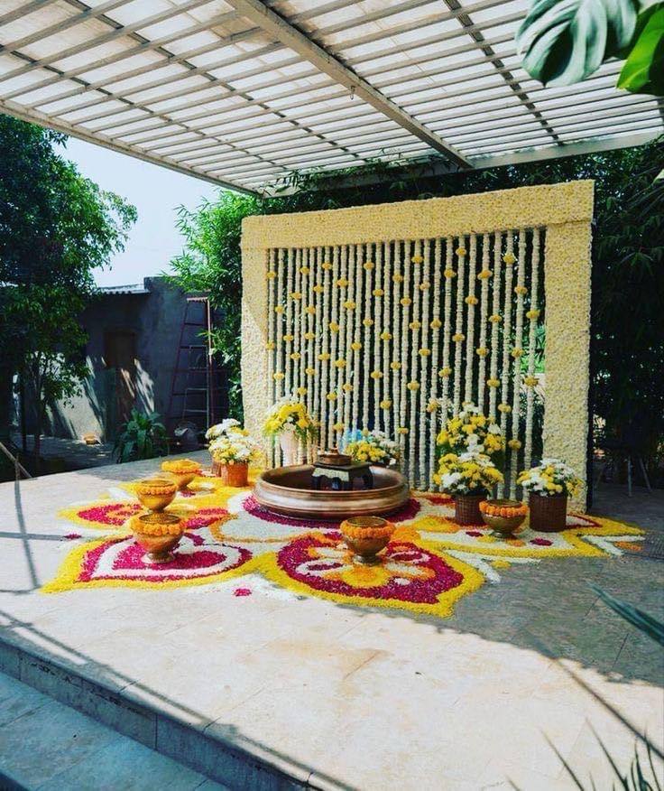Floral rangoli with brass urli and jasmine curtain